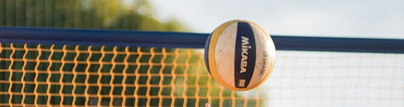 a woman reaching up to hit a volleyball