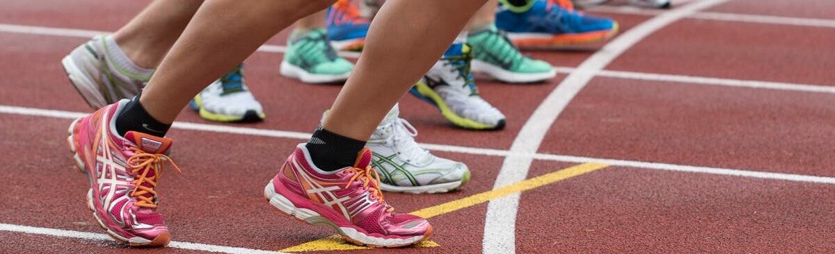 Close-up of athletes' feet at the starting line, prepared for a track race.